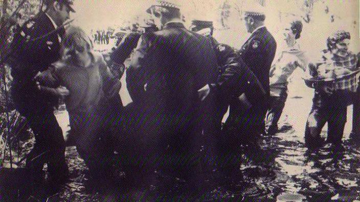 Sepia photo of people and police in lake 